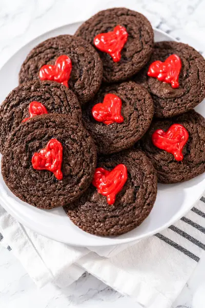 Freshly baked chocolate cookies with chocolate hearts for Valentines Day.