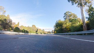 Kış günü San Luis Obispo, Kaliforniya yakınlarındaki ikonik 1. Otoyol boyunca bir araba gider. Çevresindeki manzara kahverengimsi ve bastırılmış, dalgalı tepeler ve kıyı şeritleriyle