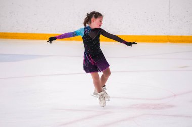 Küçük kız buz pateni pistinde artistik buz pateni yarışmasından önce pratik yapıyor..