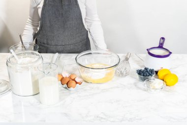 Cam kasenin içindeki malzemeleri birleştirmek, lezzetli bir vanilyalı kek hazırlamak için ustalıkla çırpmak..