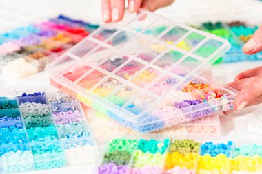 Beyaz bir masaya yerleştirilmiş çeşitli kil boncuk kutuları yaratıcı çocukların el sanatları projesini bekliyor..