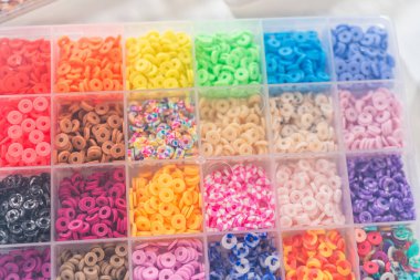 Beyaz bir masaya yerleştirilmiş çeşitli kil boncuk kutuları yaratıcı çocukların el sanatları projesini bekliyor..