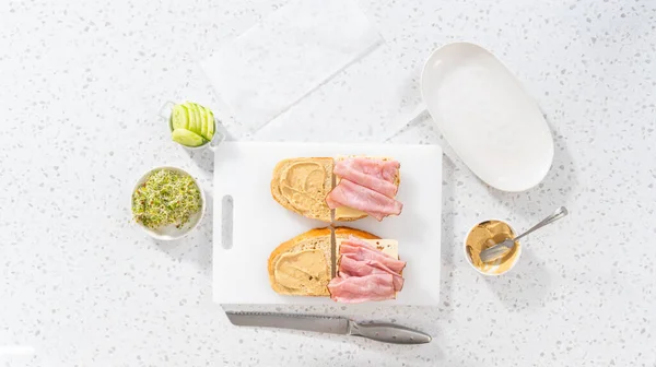 Düz Yatıyordu Beyaz Kesme Tahtasının Üzerinde Jambon Salatalık Filizli Sandviçler — Stok fotoğraf