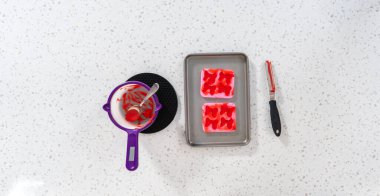Flat lay. Filling bow silicone chocolate mold with melted chocolate to make a chocolate pretzel Christmas wreath.