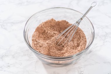 Büyük bir bardakta ıslak malzemeler karıştırarak kırmızı kadife kekler ve beyaz çikolatalı ganache kreması pişiriyorum..