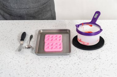 Flat lay. Filling bow silicone chocolate mold with melted chocolate to make a chocolate pretzel Christmas wreath.