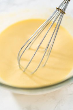 Küçük bir bardakta ıslak malzemeler karıştırmak mini vanilyalı kekler pişirmek için ombre pembe tereyağlı krema.