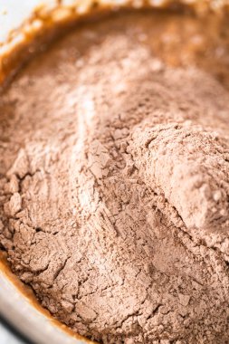 Büyük bir bardakta ıslak malzemeler karıştırarak kırmızı kadife kekler ve beyaz çikolatalı ganache kreması pişiriyorum..