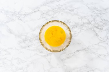 Küçük Paskalya ekmeği pişirmek için ıslak malzemeleri büyük bir bardakta karıştırıyorum..