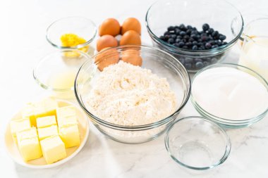 Limonlu yaban mersinli kek pişirmek için bardakların içindeki ölçülü malzemeler..