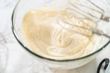 Büyük bir karıştırma kabında, malzemeler havuçlu kek için nefis krem peynirli tereyağı yapmak için ustalıkla karıştırılır..