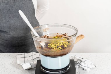 Melting white chocolate chips and other ingredients in the double boiler to prepare chocolate pistachio fudge.