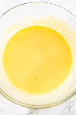 Küçük Paskalya ekmeği pişirmek için ıslak malzemeleri büyük bir bardakta karıştırıyorum..