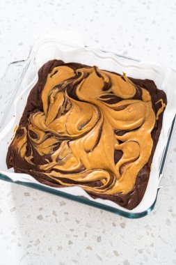 Removing chocolate fudge with peanut butter swirl from the baking pan lined with parchment