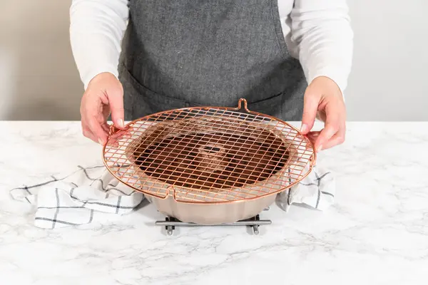 stock image With precision, the Chocolate Bundt Cake is carefully removed from the pan - placed onto a round cooling rack, preparing it for a flawless presentation and delightful indulgence.