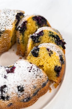 Taze pişmiş limonlu yaban mersinli kek dilimliyorum. Pudra şekerli..