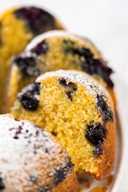 Taze pişmiş limonlu yaban mersinli kek dilimliyorum. Pudra şekerli..