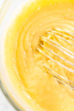 Limonlu yaban mersinli kek yapmak için büyük bir bardakta karıştırma malzemesi..