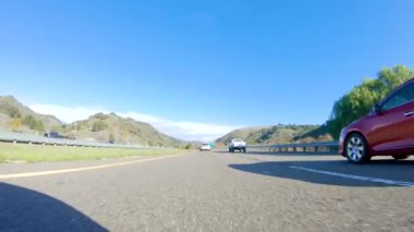 Santa Maria, California, ABD-6 Aralık 2022-Kış gününde San Luis Obispo, Kaliforniya yakınlarındaki ikonik 1. Otoyol boyunca bir araba ilerliyor. Çevresindeki manzara kahverengimsi ve bastırılmış.