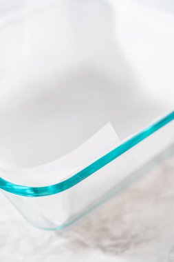 Şekerli mısır şekeri hazırlamak için kare peynirli kek tavasını kağıt kağıtla kaplamak.