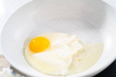 Yumurta ve filizli sandviç yapmak için tavada yumurta kızartıyorum..