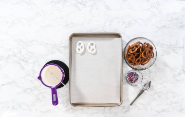 Flat lay. Dipping pretzels twists into melted chocolate to make red, white, and blue chocolate-covered pretzel twists.