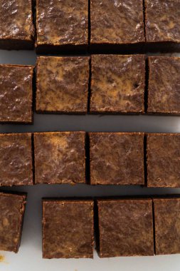 Çikolatalı fıstık ezmeli şekerlemeyi beyaz bir kesme tahtasında küçük parçalara ayırmak..