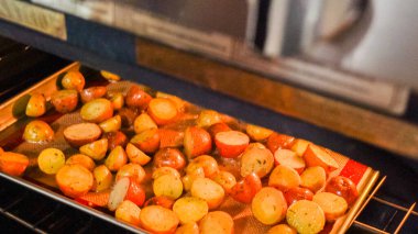 Modern bir mutfak ortamında, genç bir adam şu anda fırında baharatlı gökkuşağı patatesi kızartılarak lezzetli bir yemeğe doğru önemli bir adım atıyor..