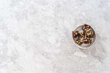 Düz yatıyordu. Beyaz tabakta ev yapımı çikolatalı fındıklı şekerleme parçaları..