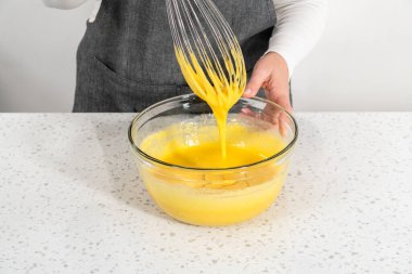 Basit bir vanilyalı kek pişirmek için ıslak malzemeleri küçük bir bardakta karıştırıyorum..