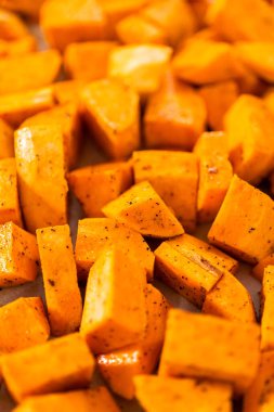 Fırında kızartılmış tatlı patates yapmak için parşömen kağıdıyla kaplı fırında tatlı patatesler..