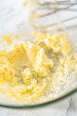 Mini vanilyalı kekler ve ombre pembe kremalı krema pişirmek için büyük bir karıştırma kabında malzemeler karıştırılıyor..