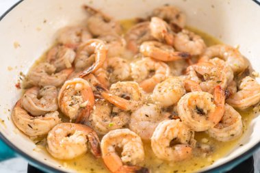 Ispanaklı sarımsaklı karides makarna hazırlamak için dökme demir tavada marine edilmiş karides..