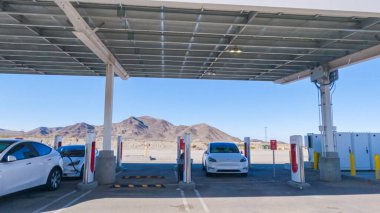 Baker, California, ABD-3 Aralık 2022-Gün boyunca Tesla bir süper şarj istasyonunda yüksek hızlı şarj altyapısını uygun ve verimli bir şekilde kullanan bir Tesla aracı görüldü.