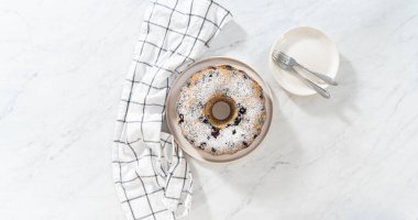 Düz yatıyordu. Taze pişmiş limonlu yaban mersinli kek dilimliyorum. Pudra şekerli..