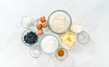 Düz yatıyordu. Limonlu yaban mersinli kek pişirmek için bardakların içindeki ölçülü malzemeler..