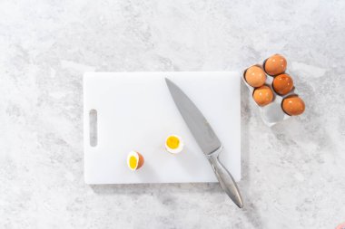 Düz yatıyordu. Beyaz kesme tahtasıyla haşlanmış yumurta kesmek..