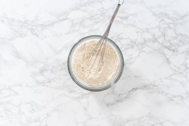 Kuru malzemeleri büyük bir bardakta çırpma kabıyla karıştırıp mini Paskalya ekmeği pişirmek..