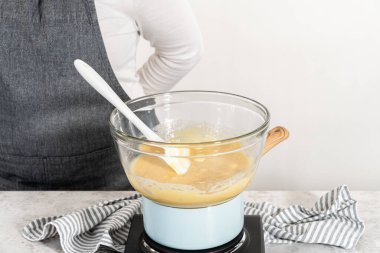 Çikolata parçacıkları ve diğer malzemeleri kaynayan suyun üzerine karıştırıp yumurta likörü hazırlıyorum..