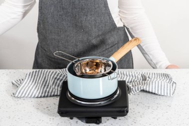 Çikolata parçacıkları ve diğer malzemeleri kaynayan suyun üzerinde karıştırarak çikolatalı şekerleme ve fıstık ezmesi karışımı hazırlıyorum..