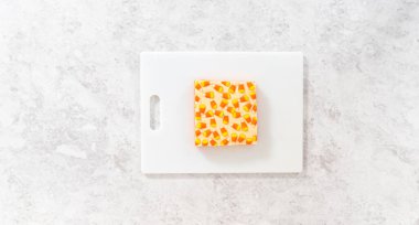 Düz yatıyordu. Beyaz bir kesme tahtasının üzerinde şekerli mısır şekerini kare parçalara ayırmak..