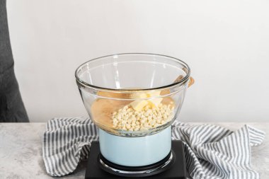 Eriyen beyaz çikolata parçacıkları ve diğer malzemeler kaynamış suyun üzerinde karışıp kızılcık fıstıklı şekerleme hazırlıyor..