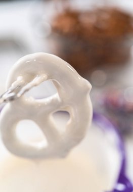 Dipping pretzels twists into melted chocolate to make red, white, and blue chocolate-covered pretzel twists.