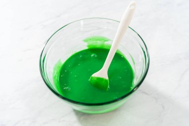 Kırmızı kalplerle yeşil şekerleme hazırlamak için küçük bir bardakta ıslak malzemeler karıştırıyorum..