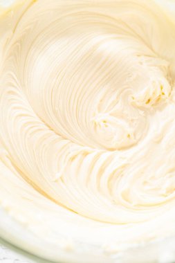 Zengin, pürüzsüz bir krem peynirli krema hazırlamak için el çırpma makinesi kullanarak malzemeleri ustalıkla birleştirirsin ki bu da kekin süslemesi için mükemmeldir..