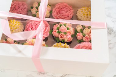 El değmemiş beyaz bir kek kutusunun içinde, her gurme kek bir sanat eseridir, tereyağı kremalı çiçeklerle süslenmiştir, canlı güllere ve lalelere benzemesi için güzelce tasarlanmıştır..