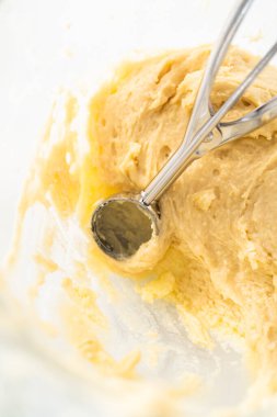 Scooping cupcake batter with dough scoop into a baking pan with liners to bake American flag mini cupcakes.