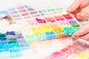 Beyaz bir masaya yerleştirilmiş çeşitli kil boncuk kutuları yaratıcı çocukların el sanatları projesini bekliyor..