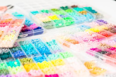 Beyaz bir masaya yerleştirilmiş çeşitli kil boncuk kutuları yaratıcı çocukların el sanatları projesini bekliyor..