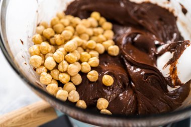 Çikolata parçacıkları ve diğer malzemeleri kaynayan suyun üzerinde karıştırarak fındıklı çikolatalı şekerleme hazırlıyorum..